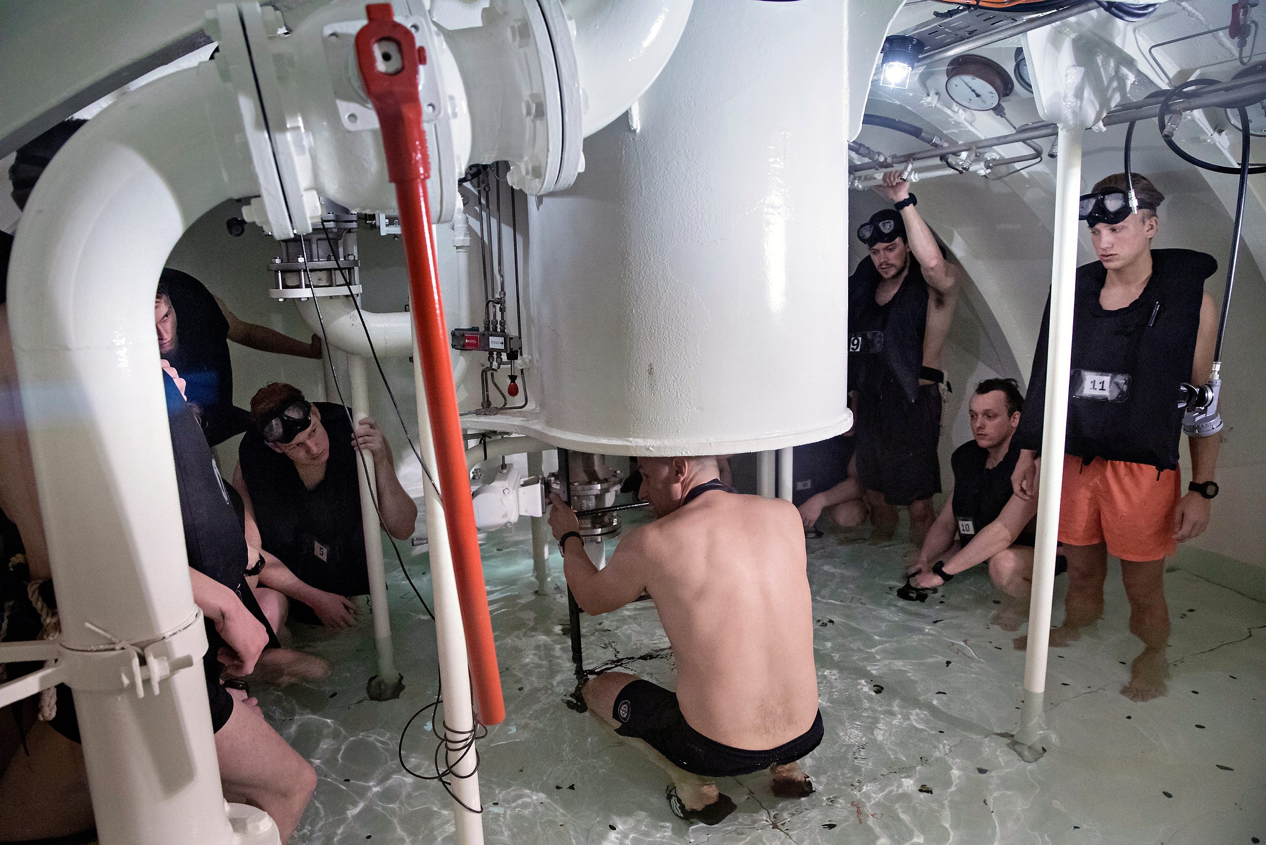 Instruktøren Jan Rune (i midten) briefer skipsdykkeraspirantene før store deler av ubåtkammeret skal fylles med vann og oppstigningen ut i tanken på 18 meters dyp skal foregå opp stigen i slusen.