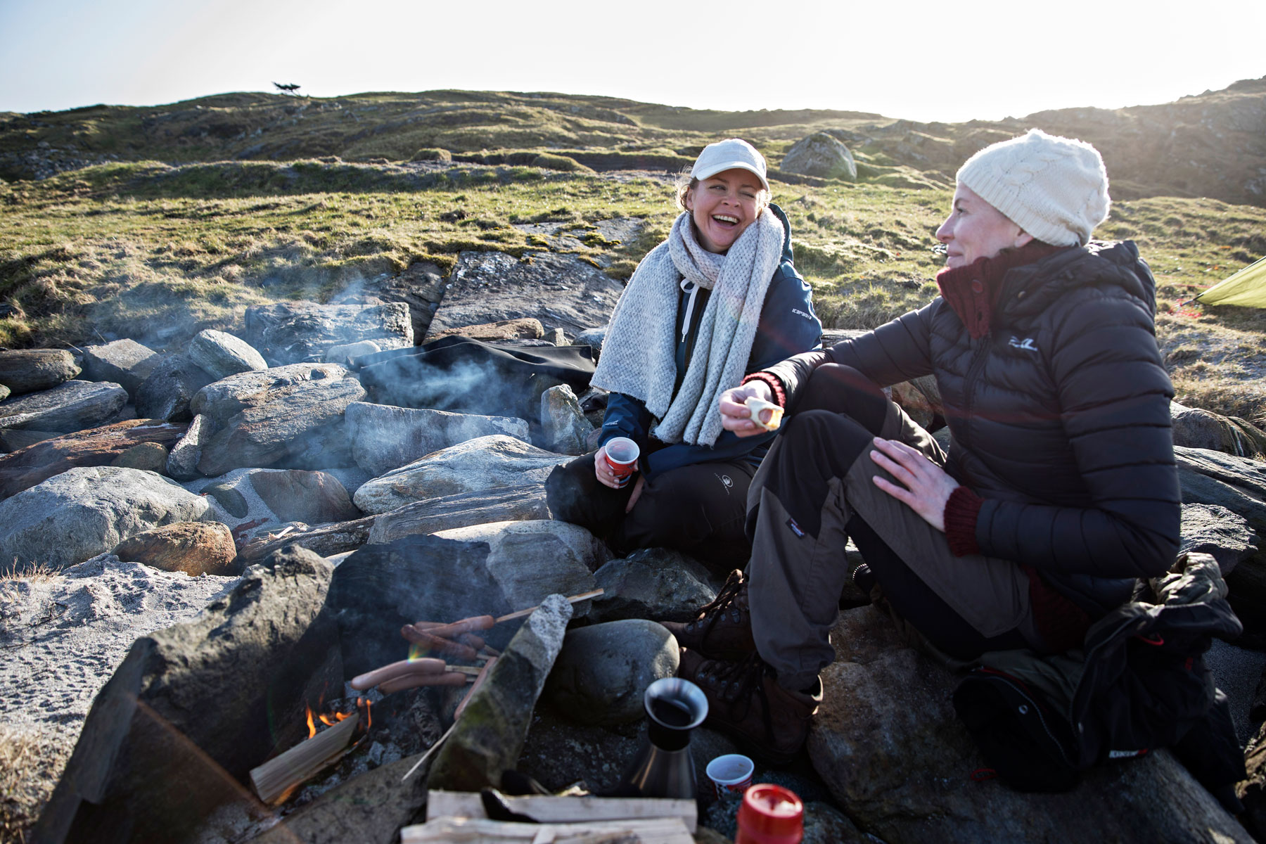 Bål, kaffe og grilling hører med til dykkingen for Elisabeth Tønnessen (til venstre) og Christine Bendiksen. Flammene gir en viss varme for kalde kropper.